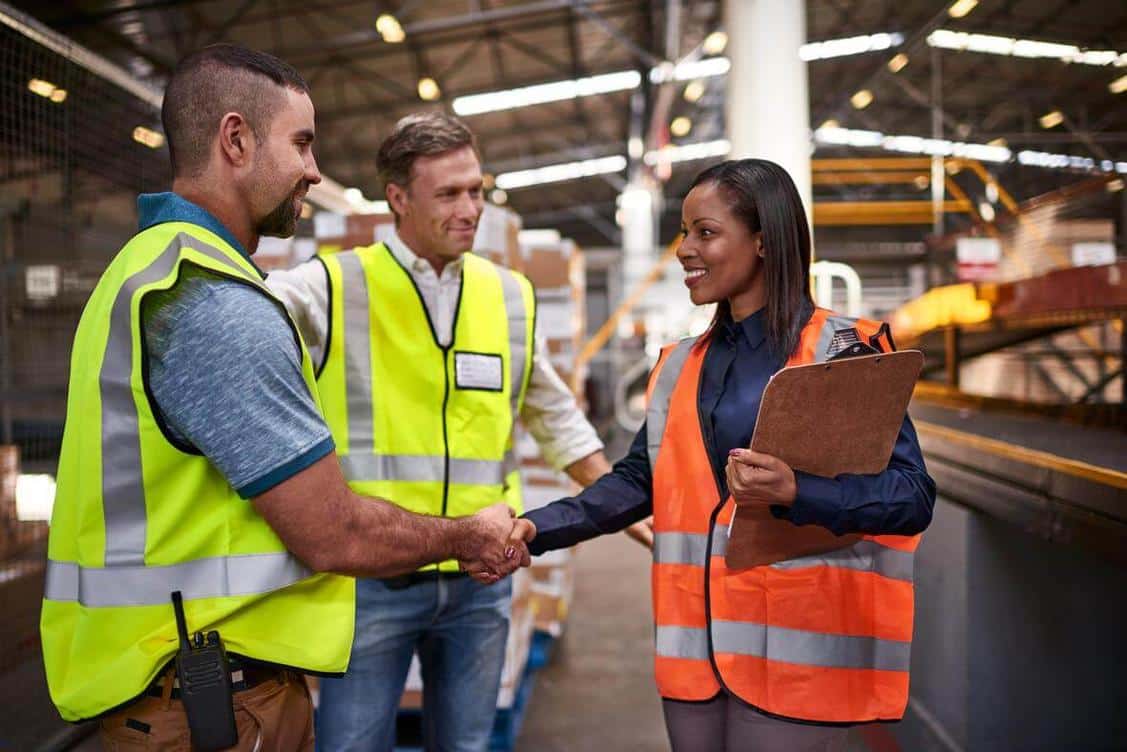 Two workers shaking hands in warehouse.