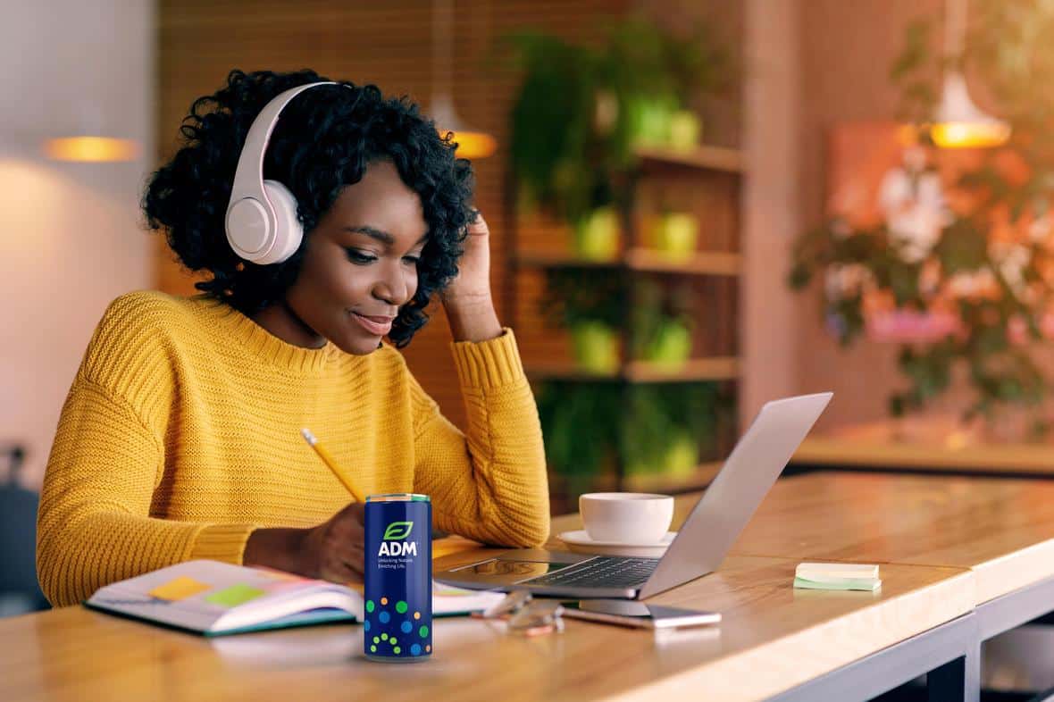 Black woman listens to music and drinks an ADM Energy Drink