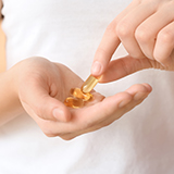 A person holding a few yellow capsules