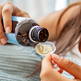 A person pouring medicine into a spoon