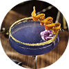 A purple cocktail in a coupe glass with garnishes