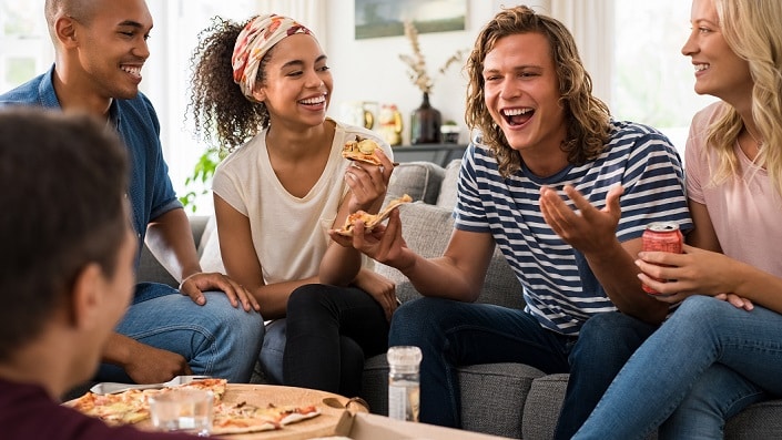 A group of people laugh together, sitting in a living room