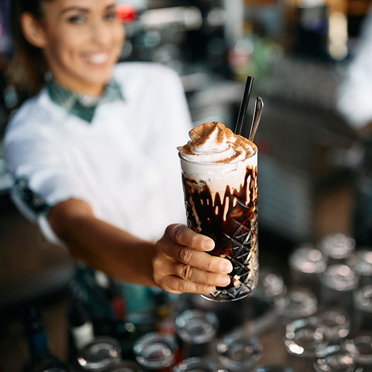 C12 smiling woman holding chocolate milkshake beverage