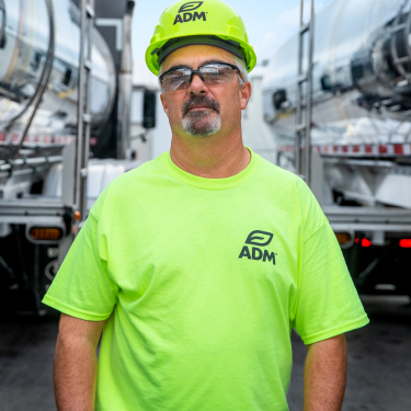 man in green adm shirt in between oil trucks